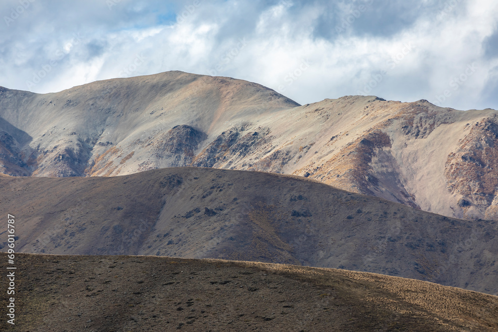 Photograph of a dry brown mountain with low level grey clouds on the South Island of New Zealand