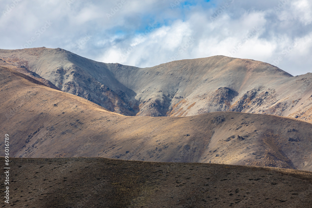 Photograph of a dry brown mountain with low level grey clouds on the South Island of New Zealand