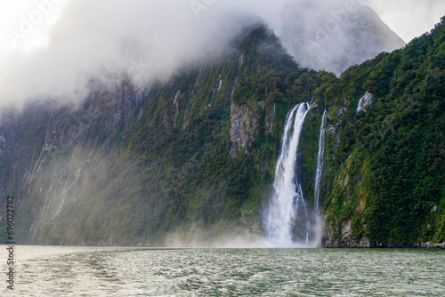 Photograph of Waterfalls from a boat on a misty and rainy day in Milford Sound in Fiordland National Park on the South Island of New Zealand