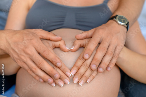 Close up young couple making a heart shape on the pregnant belly with their hands © InsideCreativeHouse