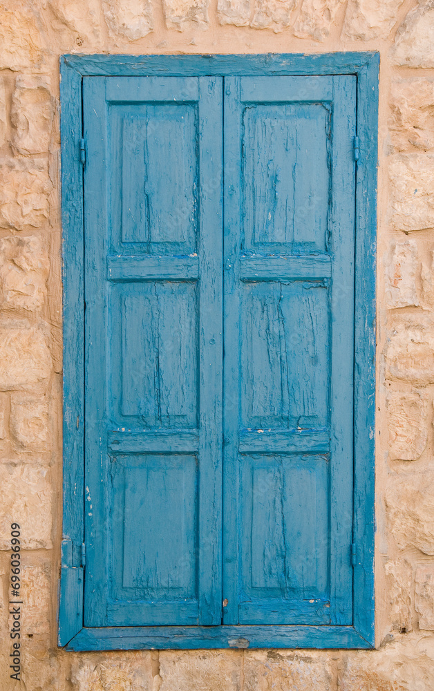 Weathered, old, blue, painted wooden shutters on a stone building in Safed, Israel