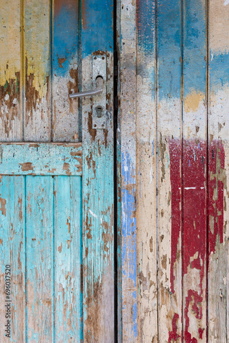 Section of a colorfully painted old door with peeling wooden boards andsilver door handle