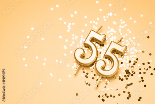 55 years celebration festive background made with golden candle in the form of number Fifty-five lying on sparkles. Universal holiday banner with copy space.