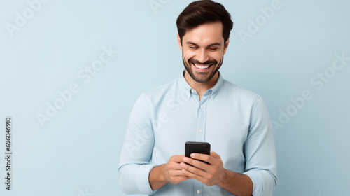 Young man smiling and holding his smartphone on a colored background © MP Studio