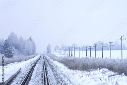 Panoramic winter view of a single-track snow-covered railroad going off into the distance. photo