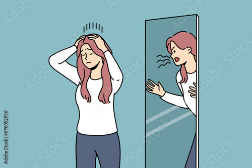 Woman is trying to restrain aggression, standing near mirror with angry reflection, for concept of mental disorder. Girl with mental problems or split personality needs help of psychotherapist