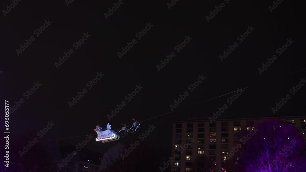 Santa Claus, riding on sleigh, Christmas. Cityscape, Santa Claus is seen on their sleigh with a gift box, riding on their reindeer as they fly over a fairy Christmas market during the Christmas season