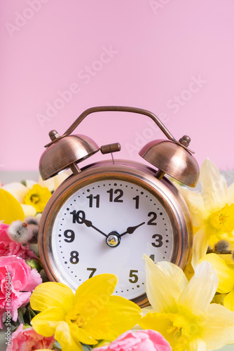Alarm clock with spring flowers. Spring time, daylight savings concept, spring forward