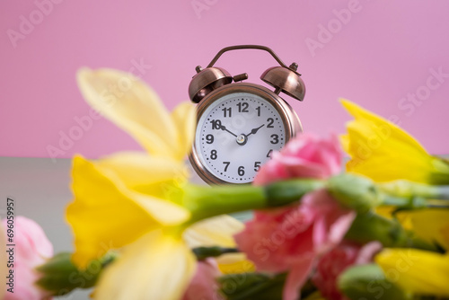 Alarm clock with spring flowers. Spring time, daylight savings concept, spring forward