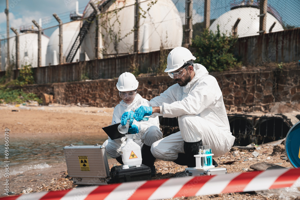 Scientist wear protection suit checking chemical and water analysis and water quality from factory. Protecting Against Hazards and Contamination. Scientist wear protection suit checking chemical and water analysis and water quality from factory. Protecting Against Hazards and Contamination.