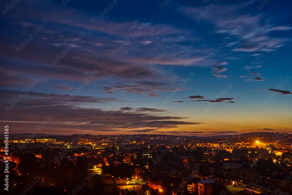  Sunset over a city skyline with illuminated buildings and colorful sky.