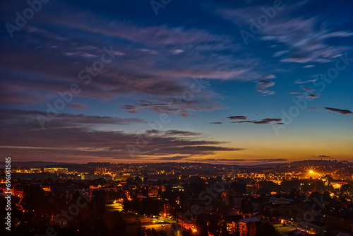  Sunset over a city skyline with illuminated buildings and colorful sky. © luchschenF