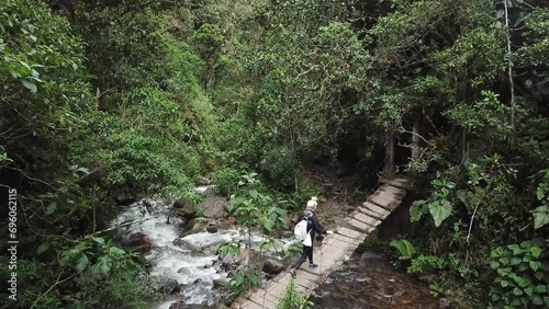 Aerial drone footage of a girl walking across a wooden suspension bridge in Cocora Valley, Colombia. Los Nevados National Natural Park near Salento. Latin America 4k footage photo