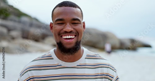 Man, face and relaxing on beach, laughing and happy in outdoors or travel to ocean for fun. Black male person, portrait and funny joke or humor in nature, peace and satisfaction on holiday or getaway photo