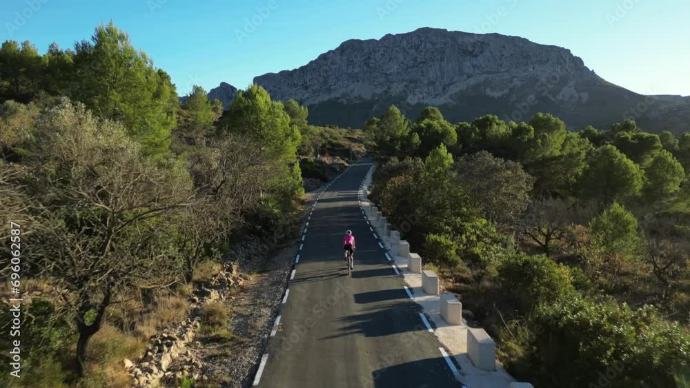 Aerial drone view of road cyclist riding a bike in mountains. A female cyclist is riding between the mountains. Athlete training on bicycle. Cycling in nature. Outdoor training. Spain. Aerial drone view of road cyclist riding a bike in mountains. A female cyclist is riding between the mountains. Athlete training on bicycle. Cycling in nature. Outdoor training. Spain.