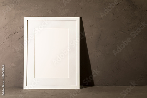 White frame leaning on dark plaster wall
 photo