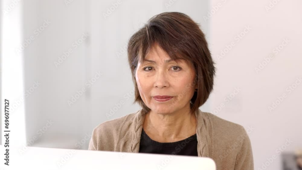 Smiling attractive stylish woman looking at camera drinking morning coffee sitting at computer, monitor in foreground. Smiling attractive stylish woman looking at camera drinking morning coffee sitting at computer, monitor in foreground.