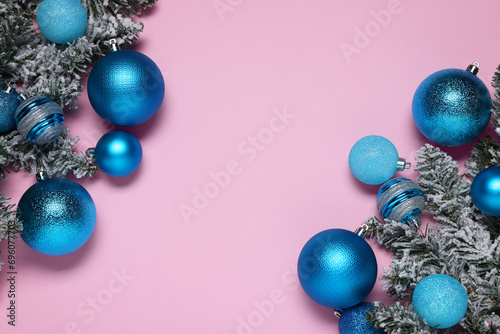 Shiny blue Christmas balls and fir tree branches with snow on pink background, flat lay. Space for text