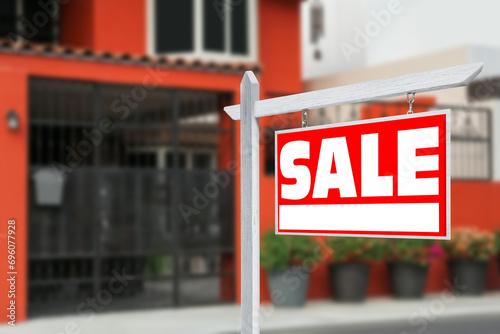 Sale sign near beautiful house outdoors. Red signboard with word