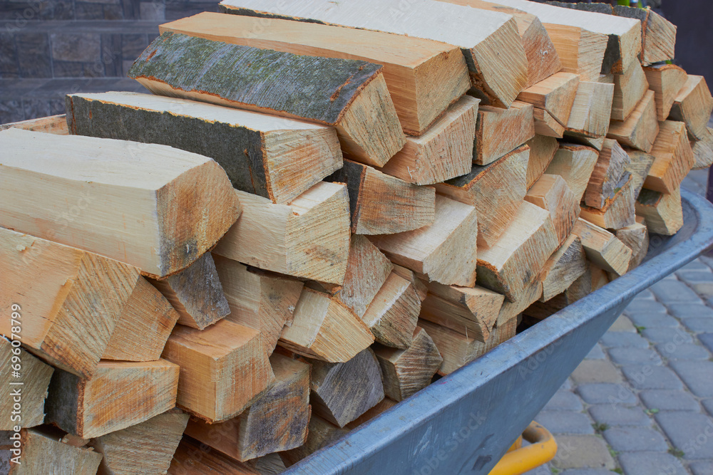close-up of firewood on a wheelbarrow, chopped firewood lies in a wheelbarrow, firewood for the fireplace close-up of firewood on a wheelbarrow, chopped firewood lies in a wheelbarrow, firewood for the fireplace