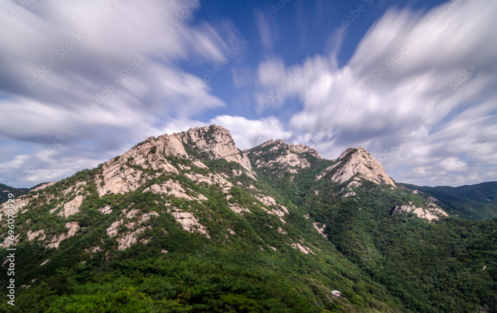 Mountains in Bukhansan National Park during day. Photo was taken with long exposure, as result of that clouds a blurred and movement of them is visible.