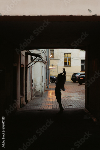 Silhouette of woman walking down a street in tunnel in rainy weather.