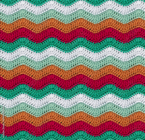 Seamless knitted pattern in the form of zigzags crocheted with threads of contrasting colors. Cotton yarn. African style.