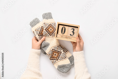 Woman with cube calendar and warm socks on white background