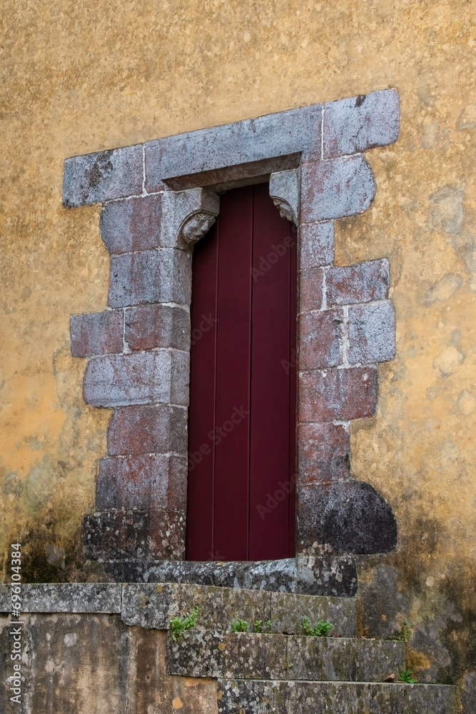 Old wooden door with red door in the wall of old house.