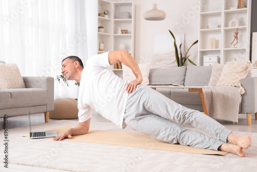 Mature man with laptop doin...