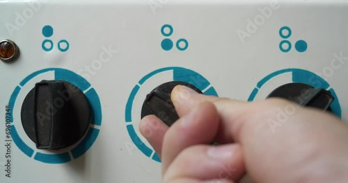 Switching on the electric stove. Man hand turns on the switch of three burner of electric stove for heating. Cinema 4K 60fps video photo