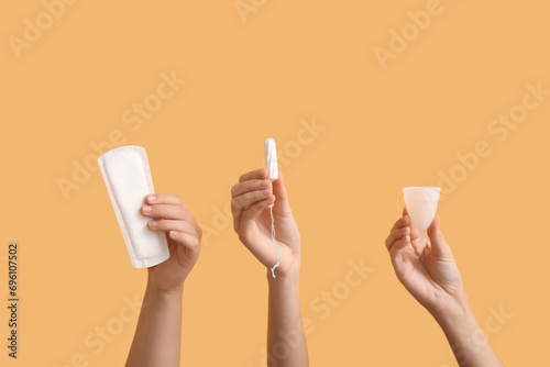 Female hands with different feminine hygiene products on color background photo