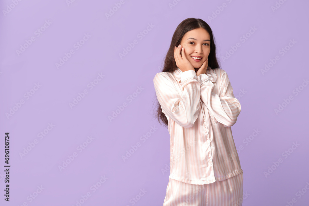 Beautiful young happy Asian woman in pajamas on purple background Beautiful young happy Asian woman in pajamas on purple background