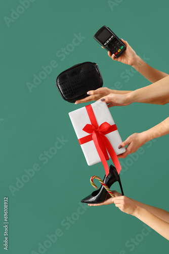 Female hands with payment terminal, bag and Christmas gift on green background. New year shopping concept © Pixel-Shot