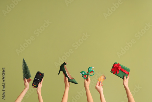 Female hands with payment terminal, shoe and Christmas decor on green background. New year shopping concept