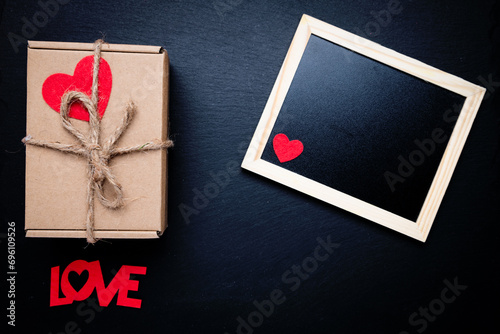Photo frame and box with a gift on a black background. Space for text. The word LOVE in a frame. Congratulations on Valentine's Day.