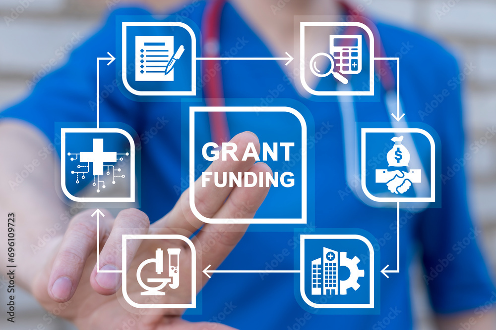 Doctor using virtual touch screen presses inscription: GRANT FUNDING. Concept of healthcare grants and funding. Medical Innovation Education Grant Fund Application Donation. Doctor using virtual touch screen presses inscription: GRANT FUNDING. Concept of healthcare grants and funding. Medical Innovation Education Grant Fund Application Donation.