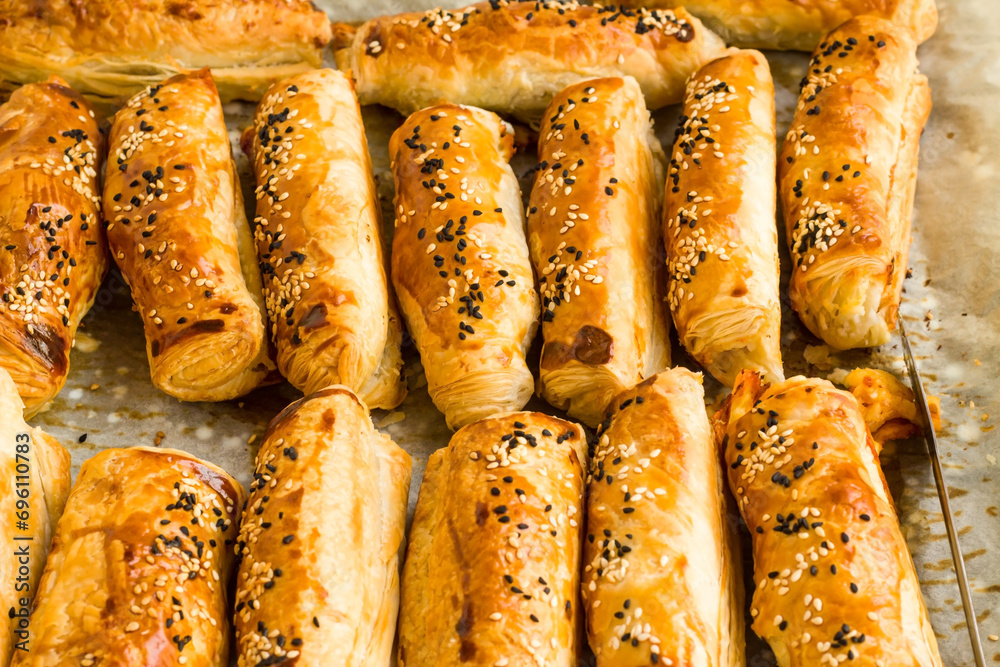 Crispy pastries with olives, sesame and black cumin on a baking tray