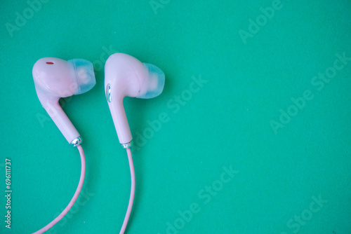 Pink wired earphones isolated over green photo
