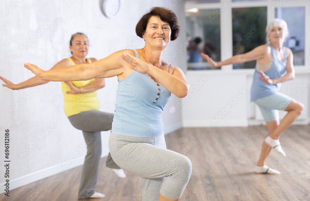 Obraz premium Group of elderly athletic women doing dancing in fitness room