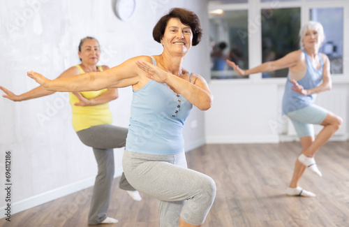 Group of elderly athletic women doing dancing in fitness room