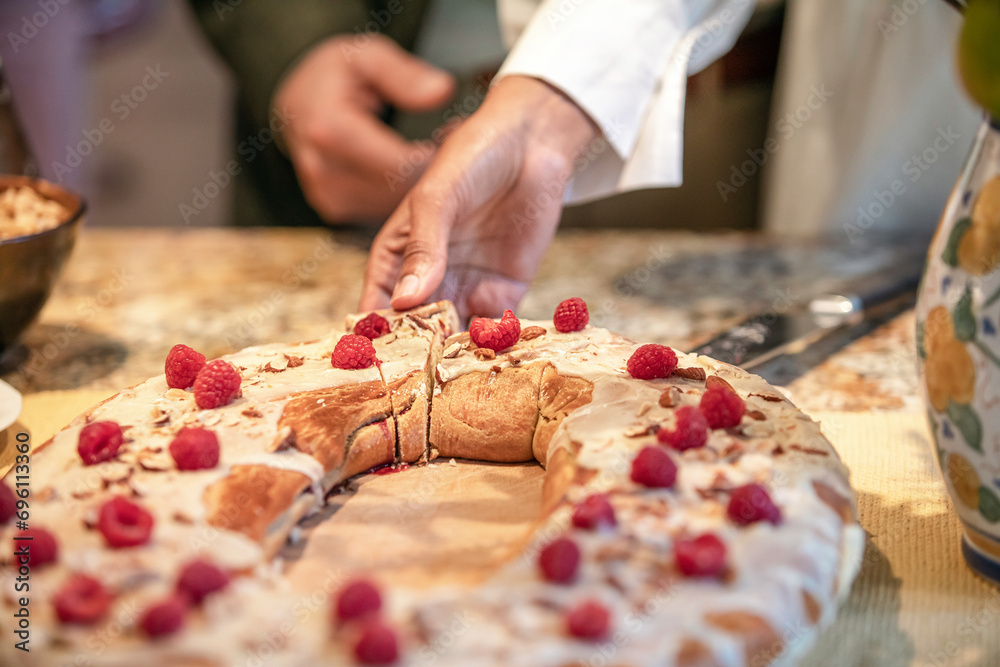 A woman reaches and takes a slice of delicious bread based pastry covered in raspberries and almonds at a wedding reception and tea A woman reaches and takes a slice of delicious bread based pastry covered in raspberries and almonds at a wedding reception and tea