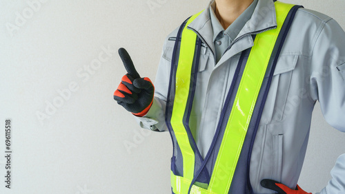 指差しポーズをする作業服の男性｜建設業・警備員・ガードマン イメージ