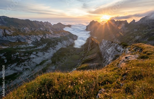 View over Saentis mountains into the valley of Meglisalp at sunrise, sun star, Rotsteinpass, high fog in the valley, Saentis, Appenzell Ausserrhoden, Appenzell Alps, Switzerland, Europe photo