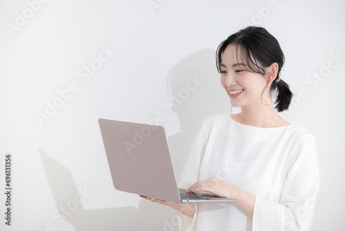 Young woman in office casual looking at laptop computer with smile White back upper body with copy space on left