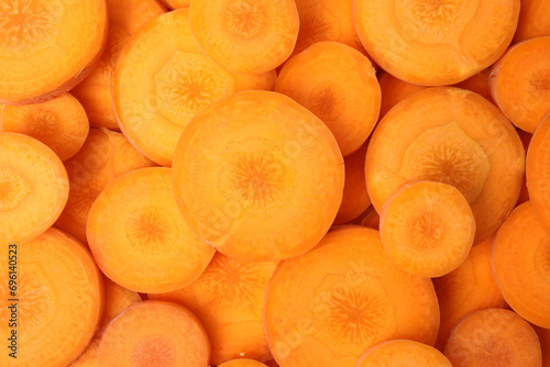 Slices of fresh ripe carrots as background, top view