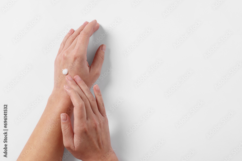 Woman with cosmetic cream on hand against white background, top view. Space for text