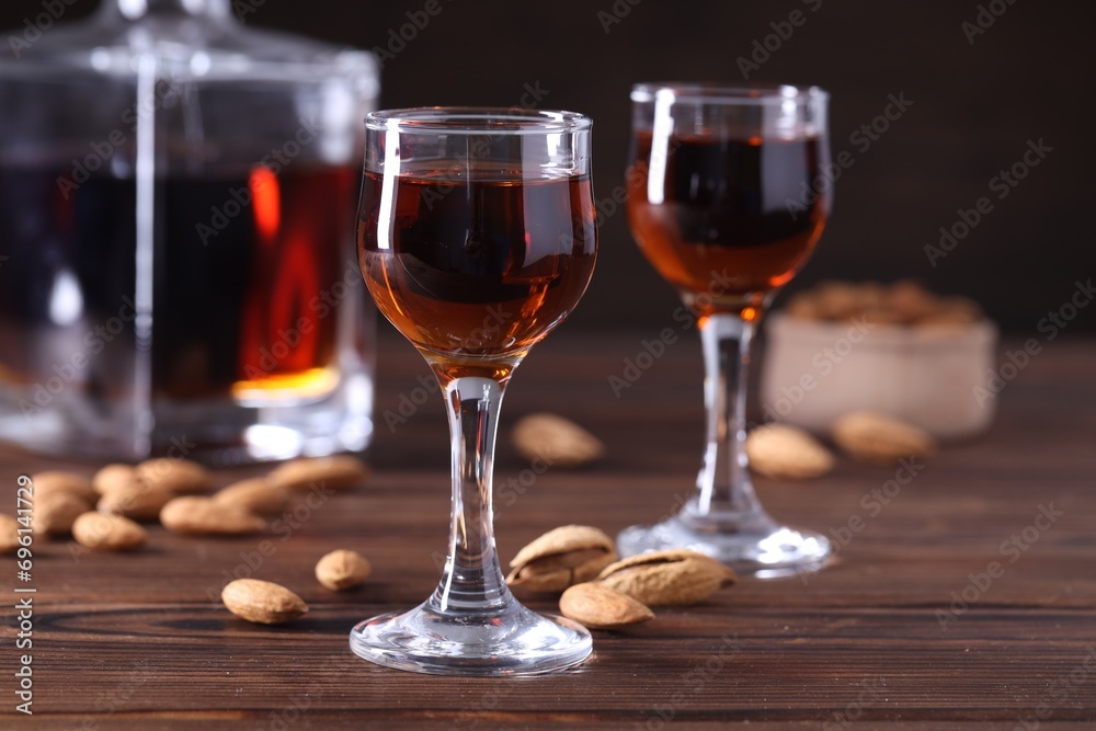 Liqueur glasses with tasty amaretto and almonds on wooden table, closeup Liqueur glasses with tasty amaretto and almonds on wooden table, closeup