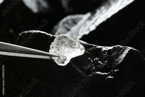 Tweezers with beautiful shiny diamond over stones, closeup © New Africa