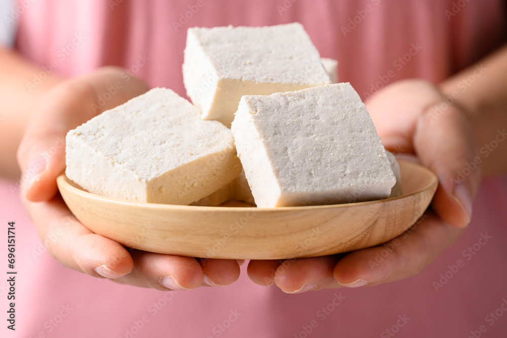 Fresh tofu in wooden bowl holding by woman hand, Vegan food ingredient in Asian cuisine, Plant based diet